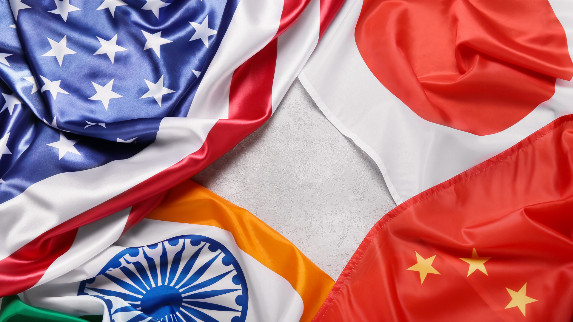 Four national flags arranged in a circular pattern with a blank space in the center.