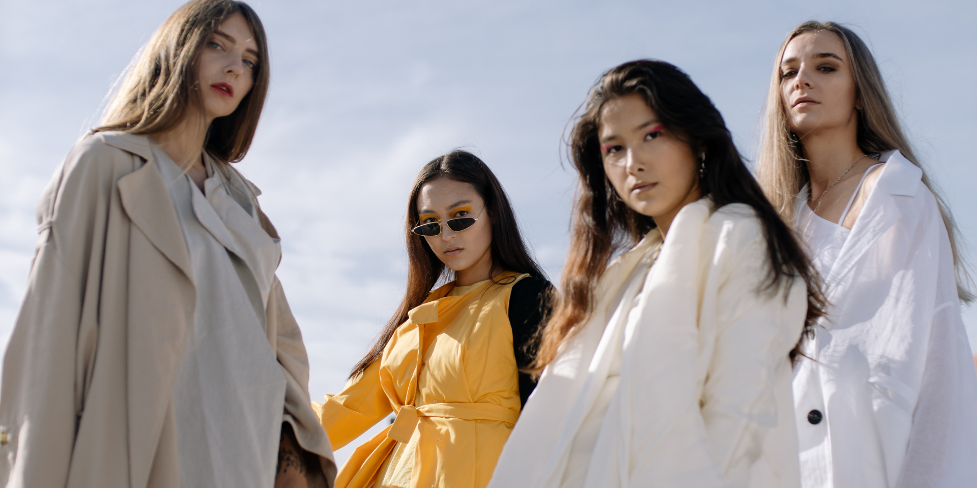Group of four models in modern outerwear posing outdoors, showcasing contemporary fashion design.